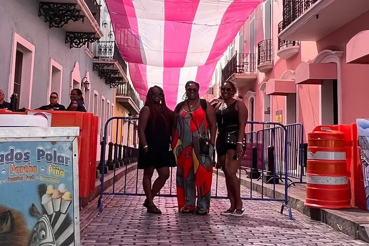 Friends under a painted flag canopy on a pastel street